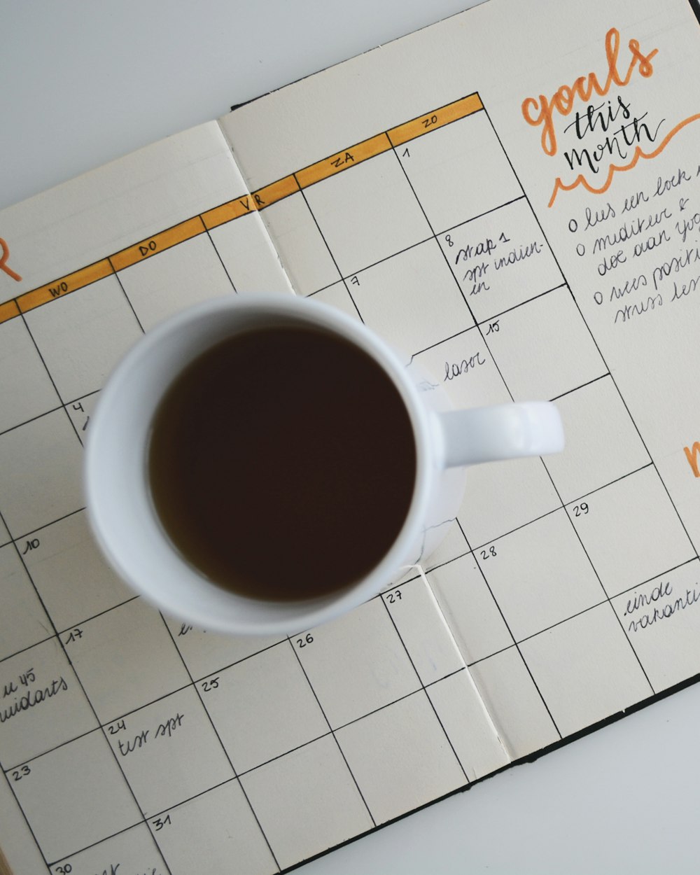 Un café sobre un planificador de metas del mes — finanzas en calma